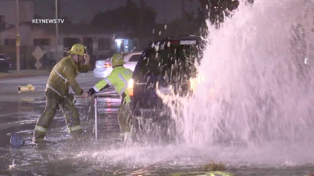 Firefighters Work to Turn Off Water After Vehicle Collision with Hydrant