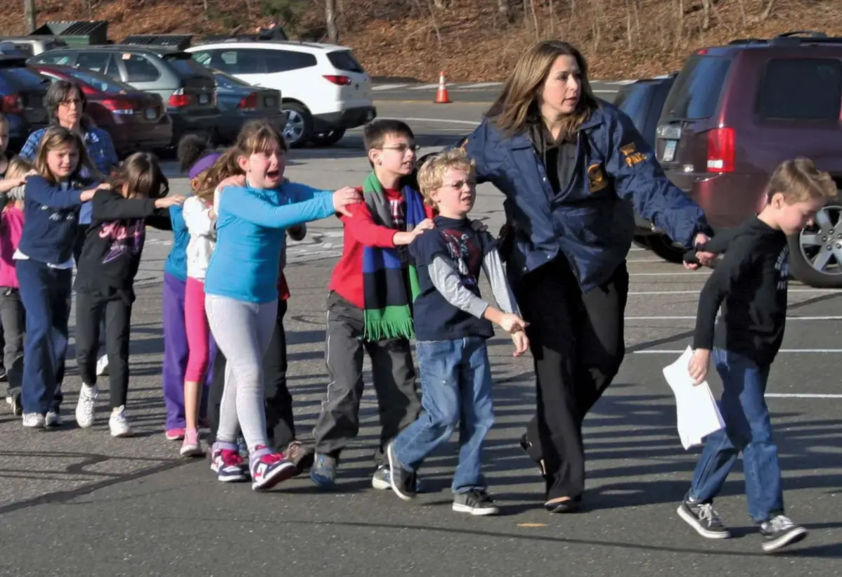 A police officer leads Sandy Hook students to safety
